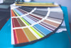 A fandeck of paint color chips fanned out on top of a blue surface.
