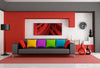 Front view of a black couch with red, yellow, purple, green and blue pillows, in front of a red and grey wall.