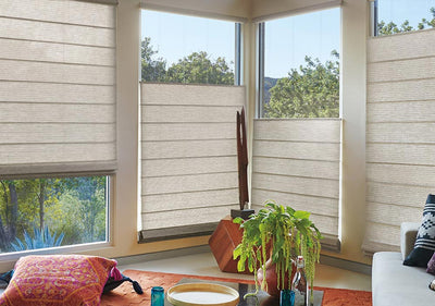 A living room with four large windows displaying Hunter Douglas Alustra Woven Textures in beige, available at Gleco Paint in PA.