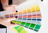 A person's hands holding a fandeck of paint color chips.