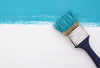 Blue paint strip across a white surface, with the paint brush sitting on top.