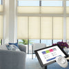 Large windows with Hunter Douglas beige window shades, with an overlay of a tablet showing the PowerView Motorization app.
