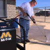 A man using a Mi-T-M pressure washer outside.