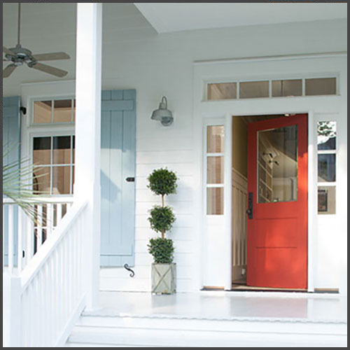 A red front door on a white painted house with light blue painted shutters.